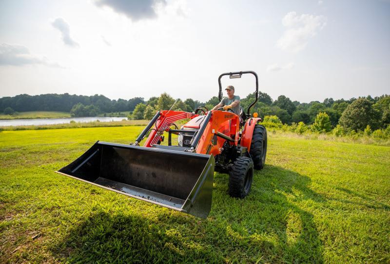 Man on orange tractor by a lake